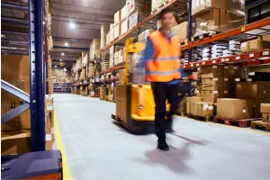 Uitzendkracht loopt door een magazijn met een palletwagen