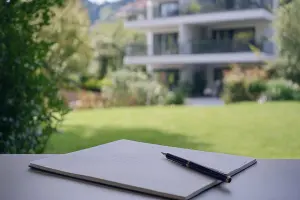 Notebook en pen met huis op achtergrond