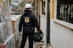 Medewerker staat met een gereedschapskist op de bouwplaats
