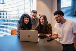 Vier medewerkers vergaderen met laptop in het midden
