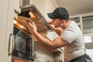 Medewerker repareert afzuiging in de keuken