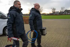 Medewerkers lopen met gereedschap naar de huisvestinglocatie