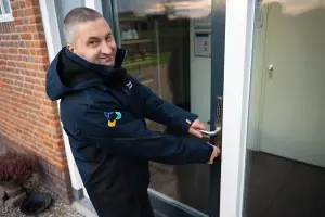 Medewerker lacht naar de camera terwijl hij de deur op slot draait