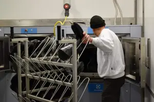 Medewerker haalt schone laarzen uit schoonmaakmachine