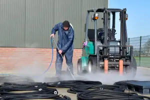 Medewerker maakt slangen schoon met hogedrukreiniging