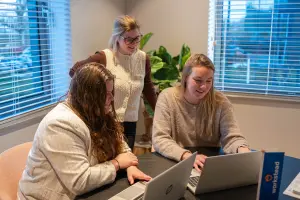 Drie medewerkers zijn samen bezig op de computer