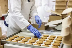 Medewerker legt vers gebakken koekjes in een doos